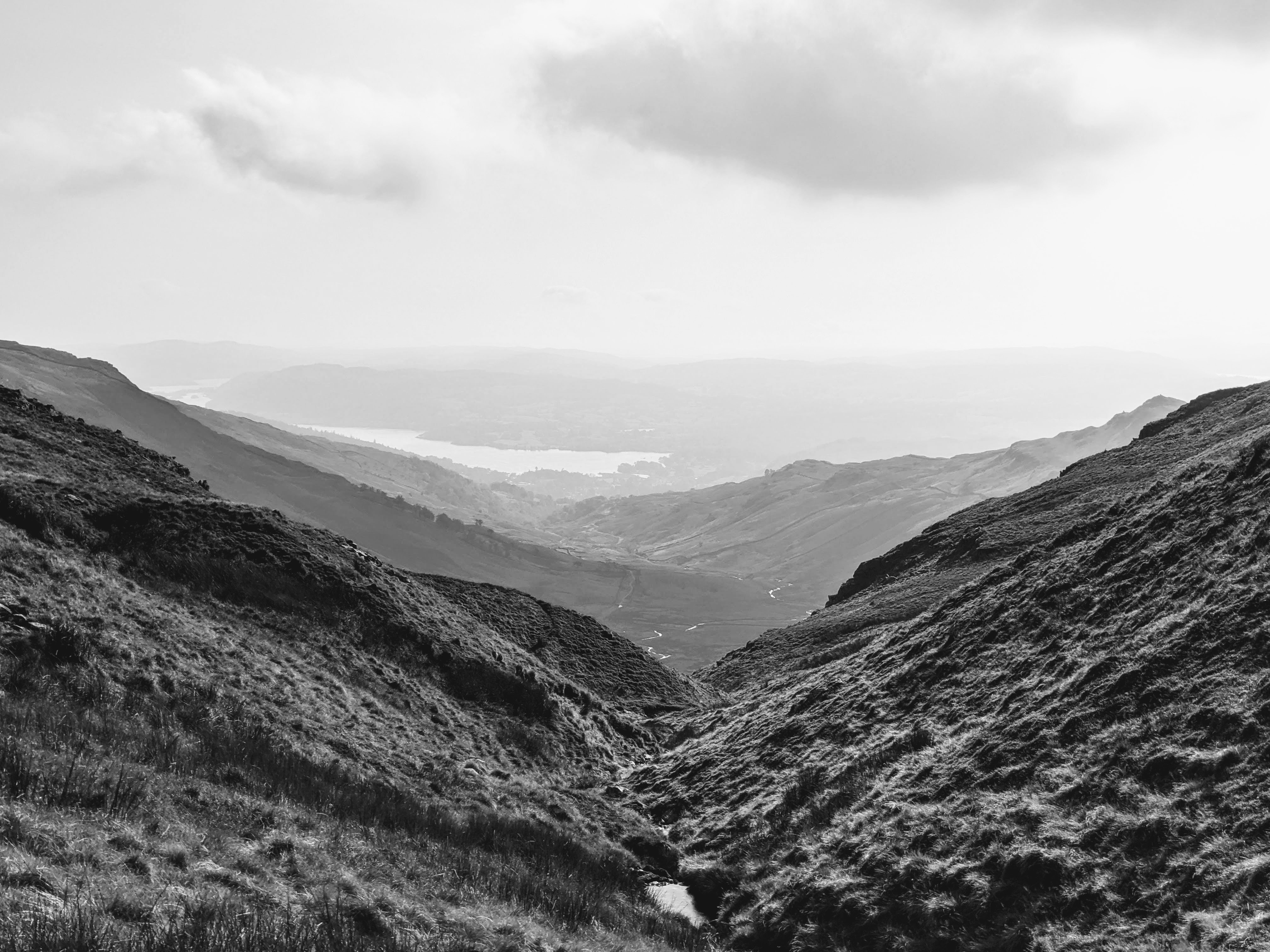 A black and white landscape photograph looking down a valley towards Ambleside and lake Windermere.