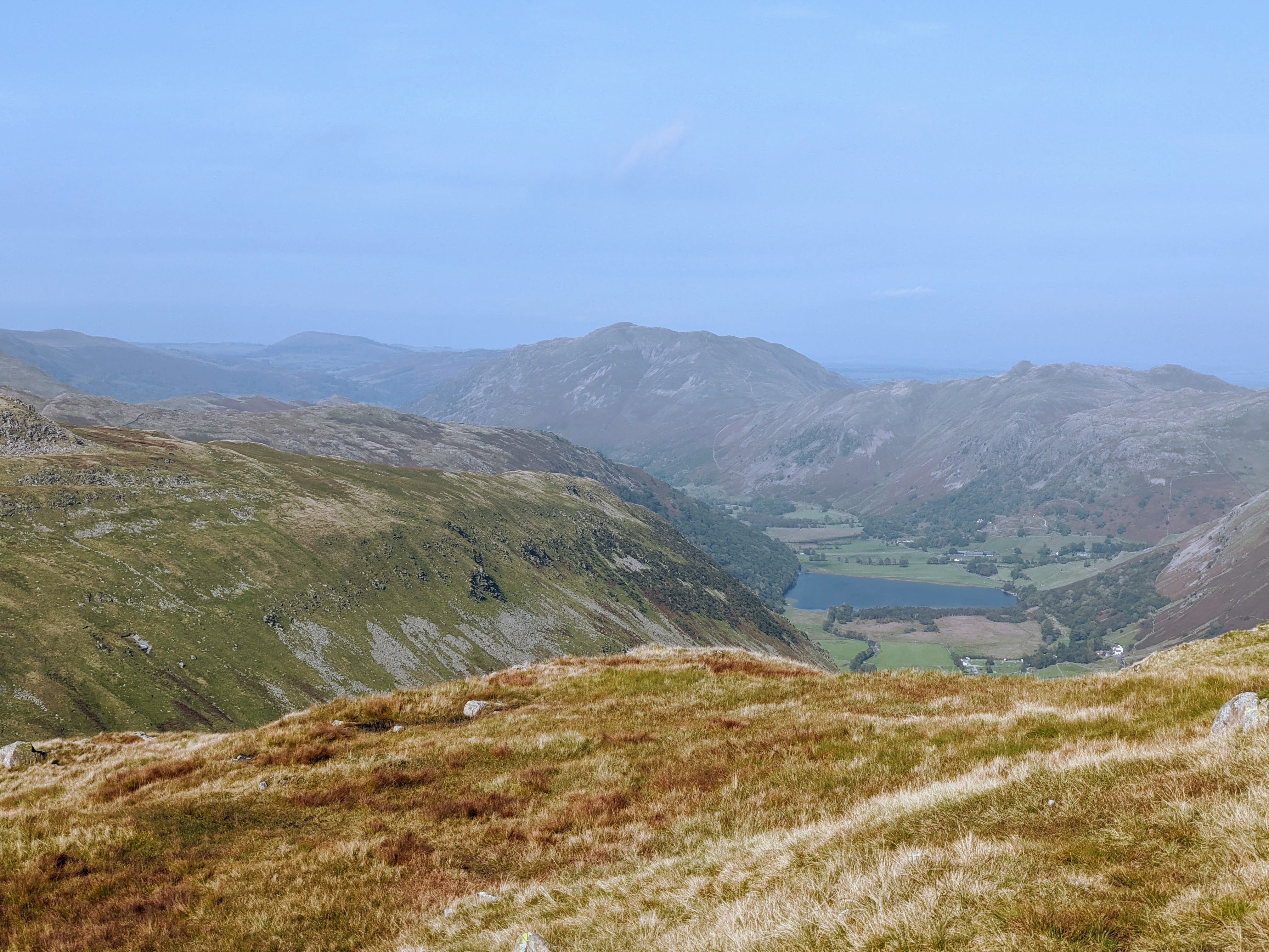 A landscape photograph from the summit of red screes, looking over a town in the valley below.